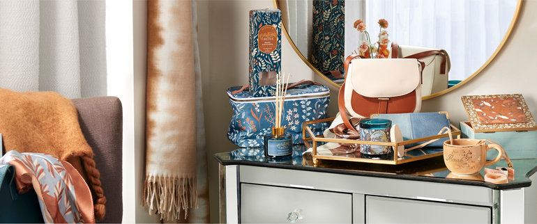 Lifestyle image with fashion accessories and gifts in blue, teal, tan and amber colors.